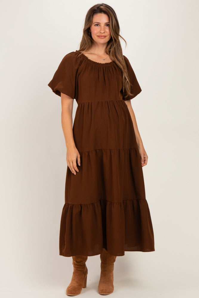 woman wearing a brown maternity maxi dress with short puff sleeves and tiered ruffle details