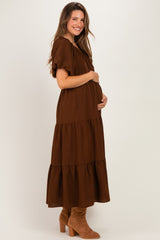 woman wearing a brown tiered maternity dress and cradling her baby bump