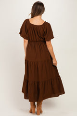 woman wearing a brown tiered maxi maternity dress with short sleeves and a fitted waist, showing a baby bump