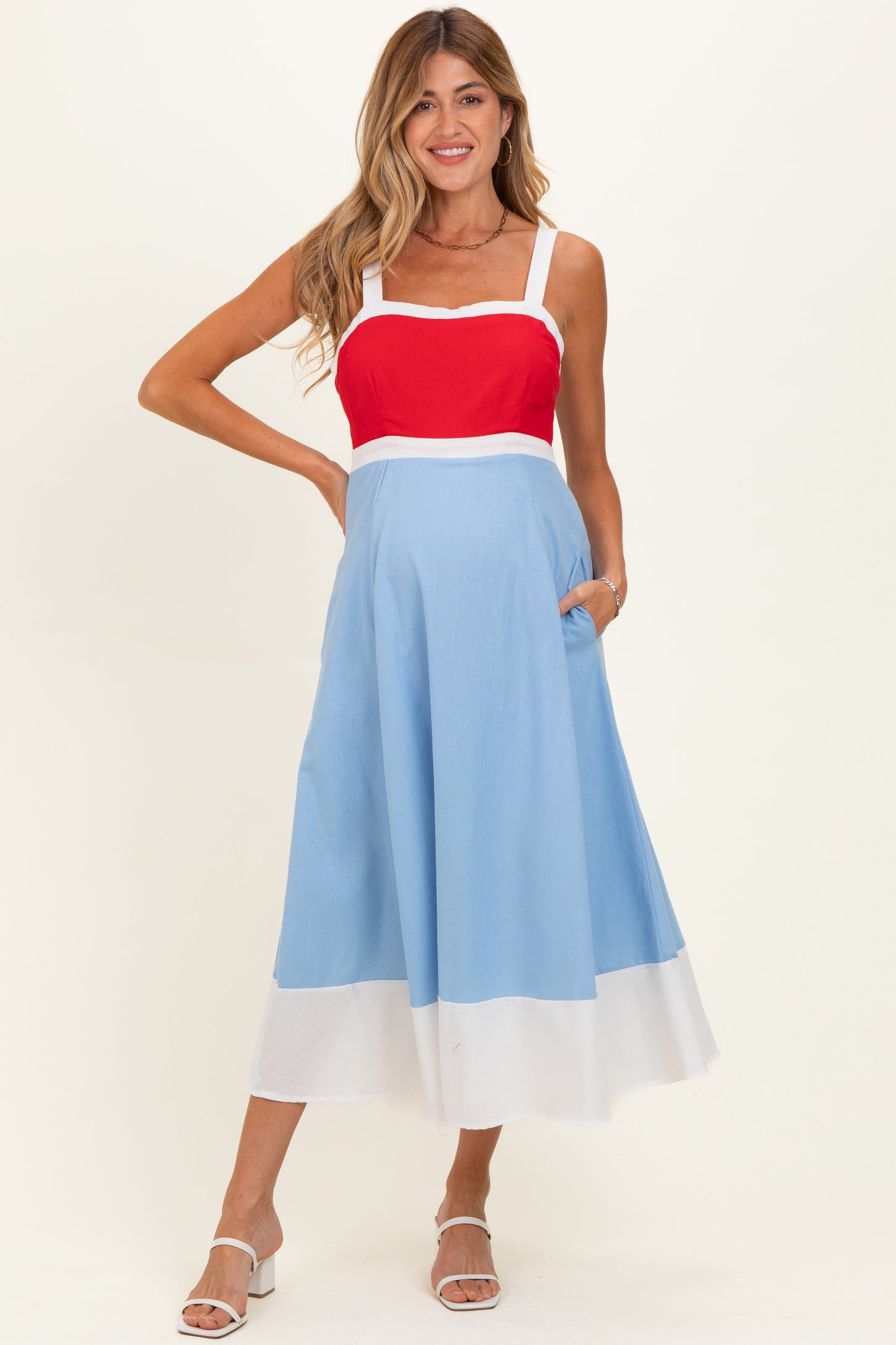 woman wearing a red and light blue color block maternity dress with pockets and a flowy skirt