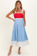 woman wearing a red and light blue color block maternity dress with pockets and a flowy skirt