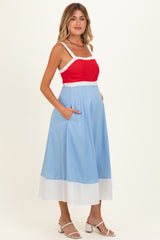 woman wearing a red and light blue maternity dress with a white hem and pockets, showing her baby bump