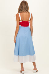 woman wearing a red cropped top and a blue and white color-blocked midi skirt, showcasing her baby bump from behind