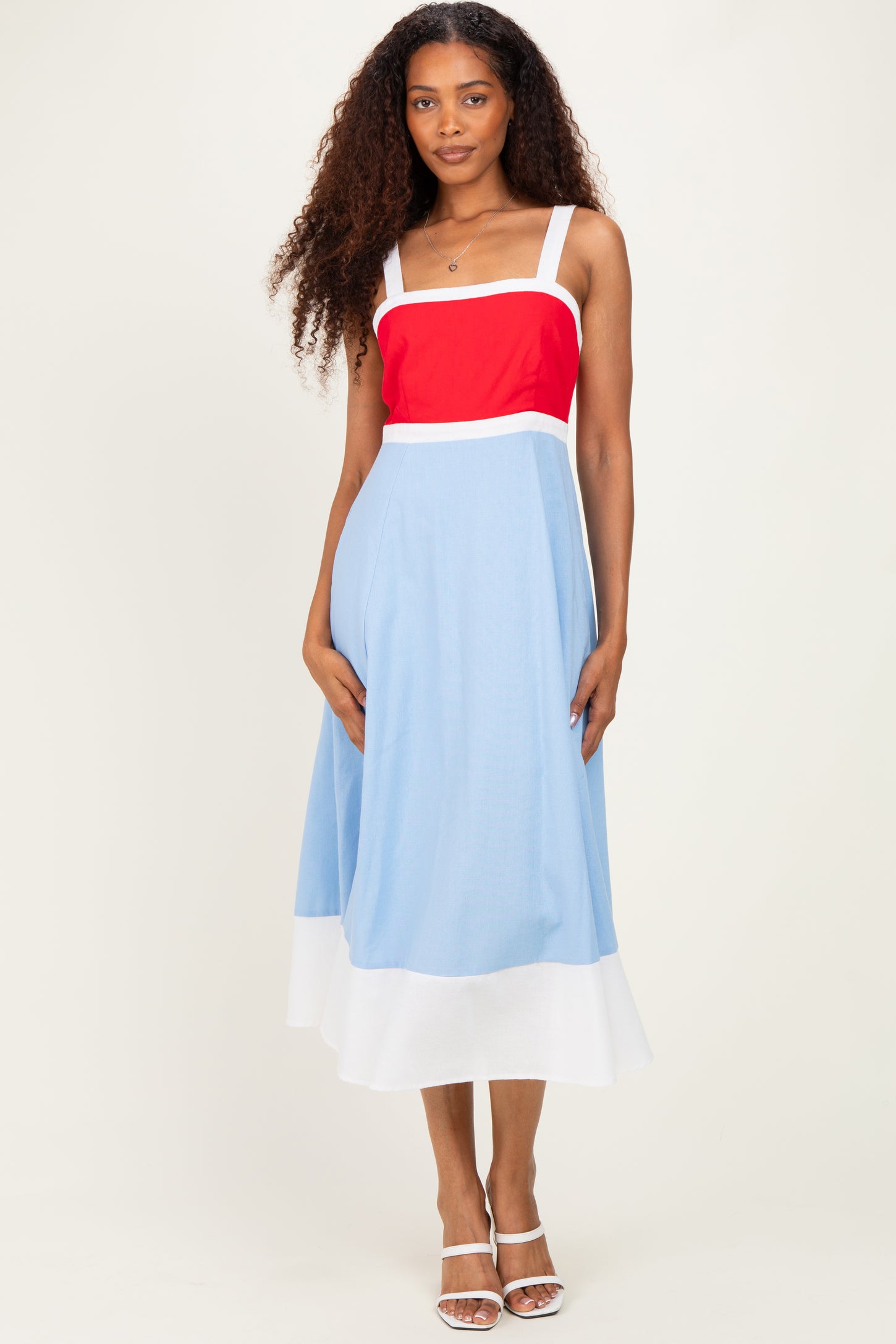 woman wearing a red and blue color block midi dress with a fitted bodice and flared skirt