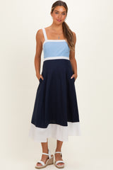woman wearing a blue and navy color-blocked maternity dress with a fitted bodice and flowing skirt, pockets included