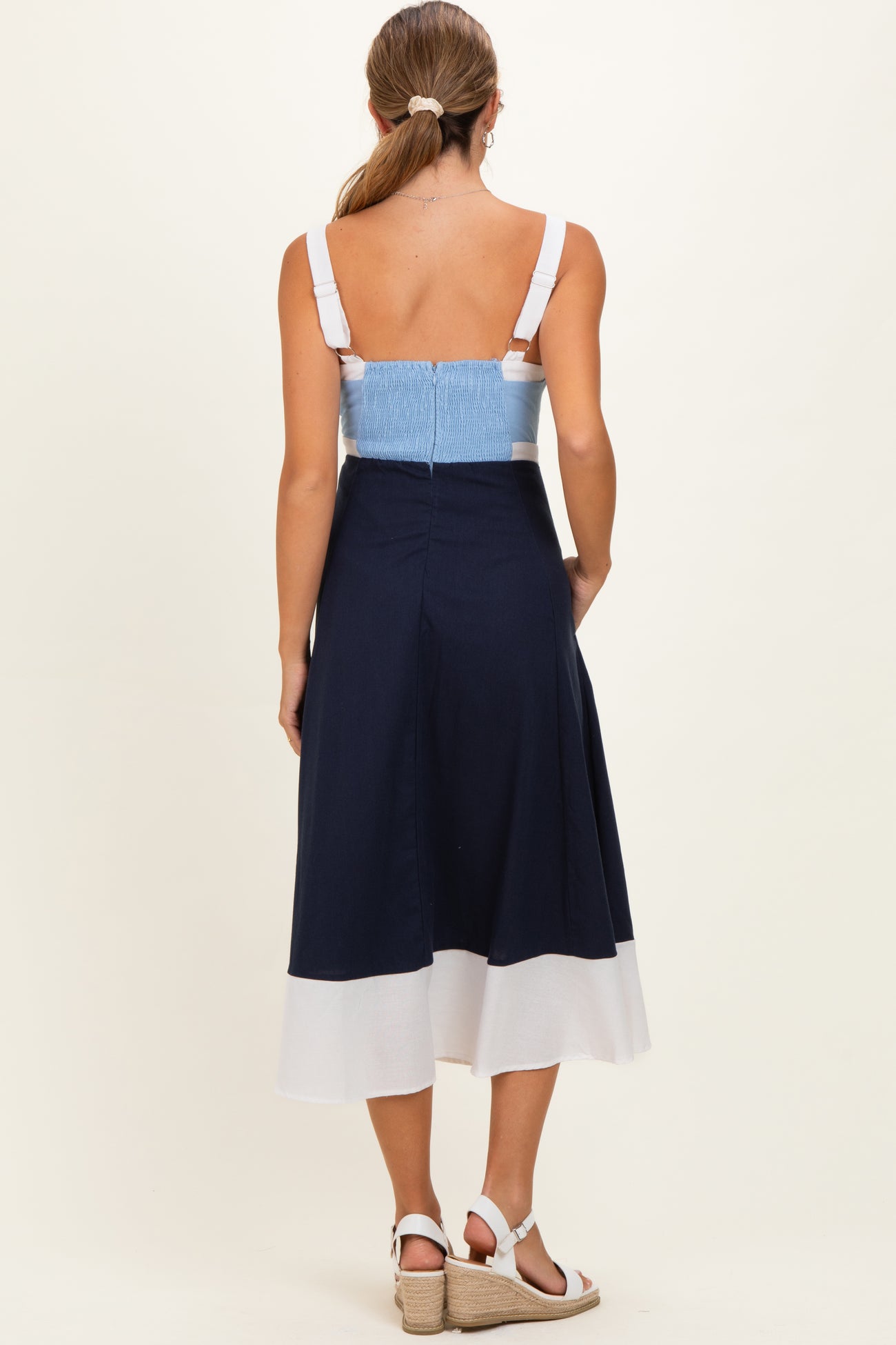 woman wearing a navy and white colorblock maternity dress with a smocked bodice, showing her back