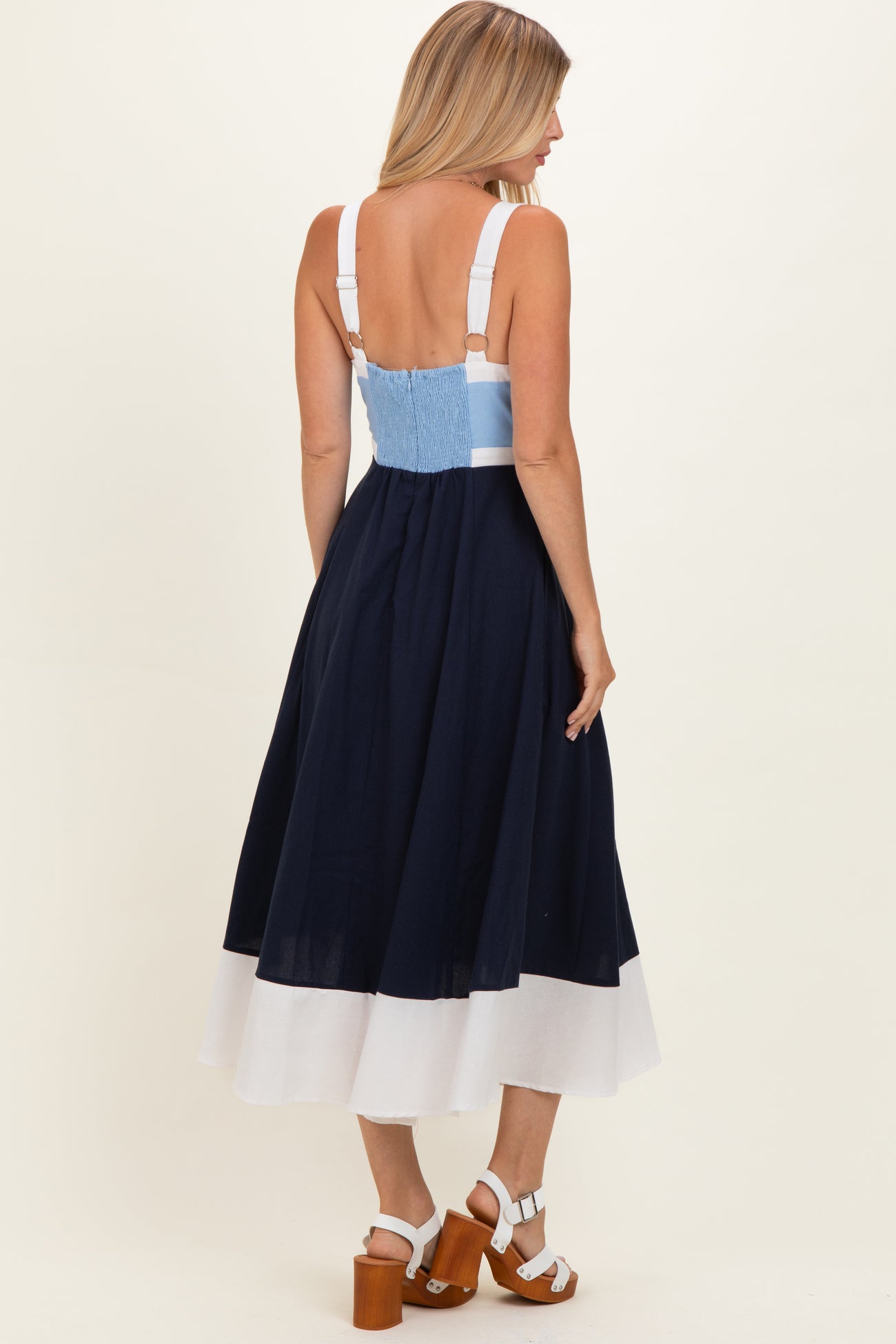 woman wearing a navy and white color-block midi dress with adjustable straps and a smocked back detail