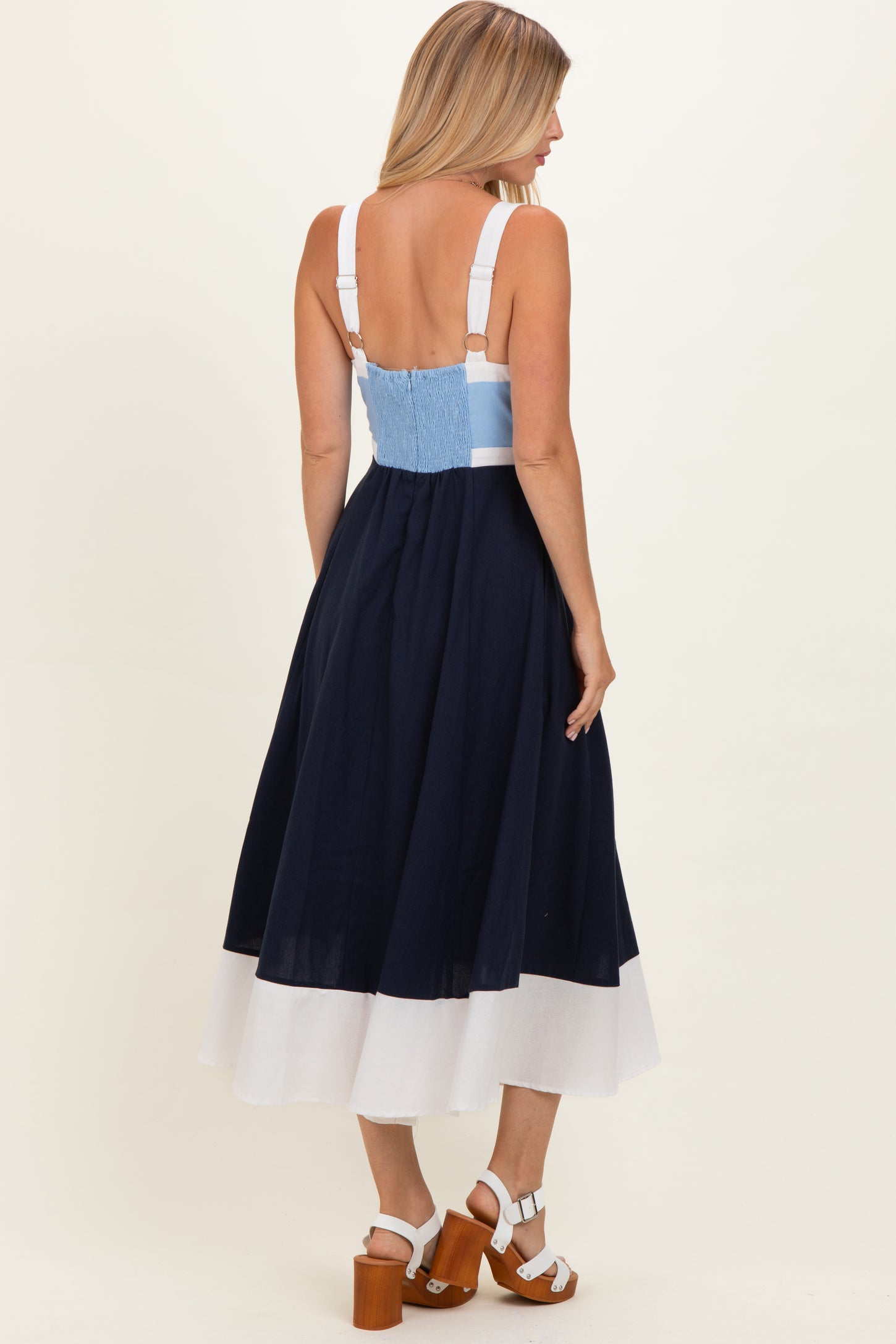 woman wearing a navy and white color-block midi dress with adjustable straps and a smocked back detail