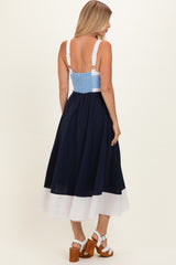 woman wearing a navy and white color-block midi dress with adjustable straps and a smocked back detail