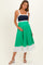 woman wearing a navy blue and green color block maternity dress with a fitted bodice and flowy skirt, holding her baby bump