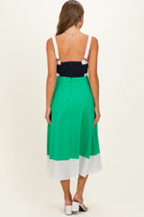 woman wearing a color-blocked green and white maternity dress with a navy blue bodice, showing her back