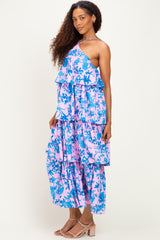 woman wearing a pink and blue floral tiered maxi dress with one shoulder strap and ruffled layers