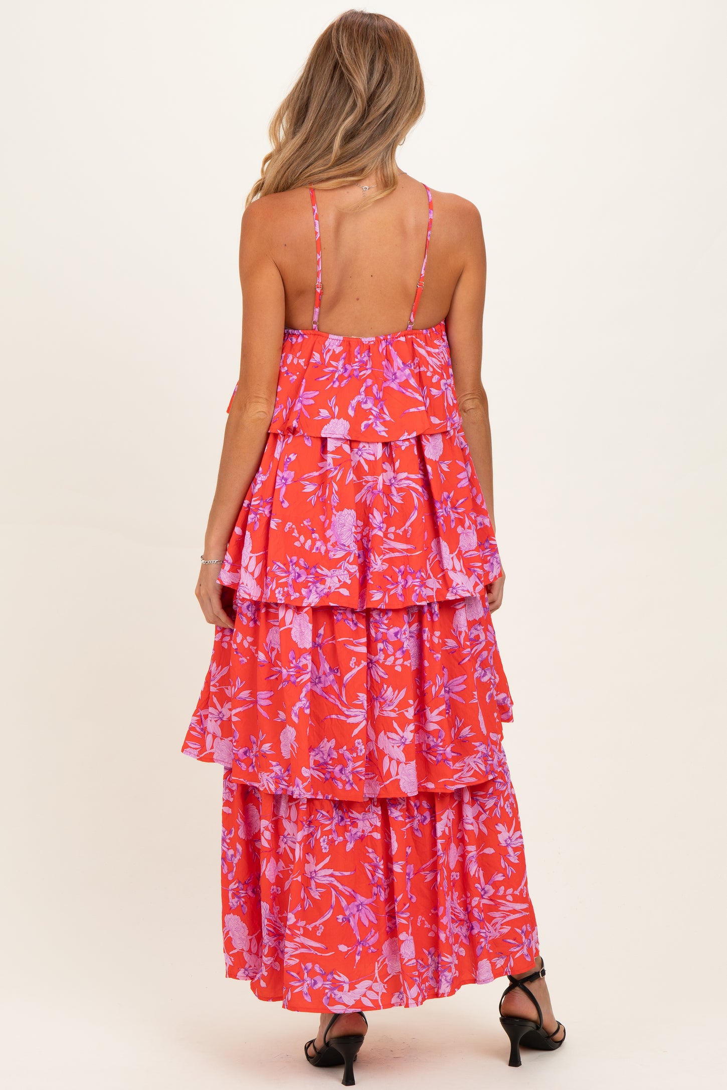 woman wearing a vibrant red floral maternity dress with layered ruffles and spaghetti straps