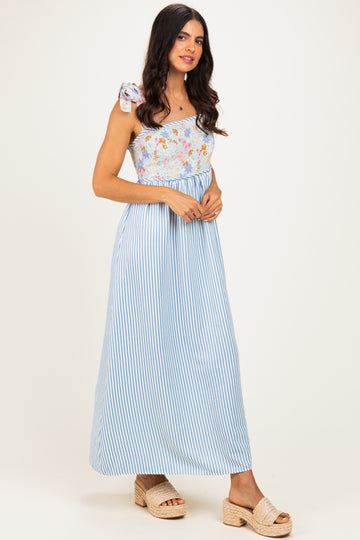 woman wearing a blue and white striped maxi dress with a floral one-shoulder top and a bow detail on the strap