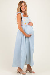 woman wearing a floral and striped maternity maxi dress, holding her baby bump