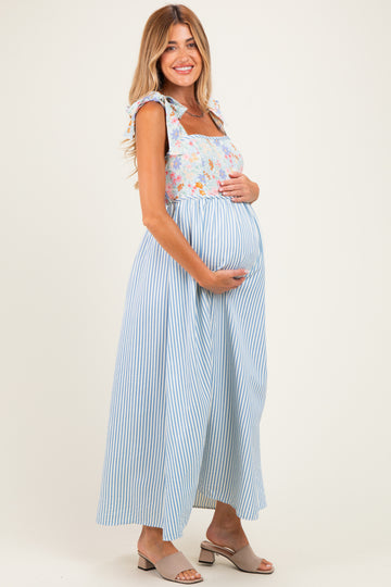 woman wearing a floral and striped maternity maxi dress, holding her baby bump
