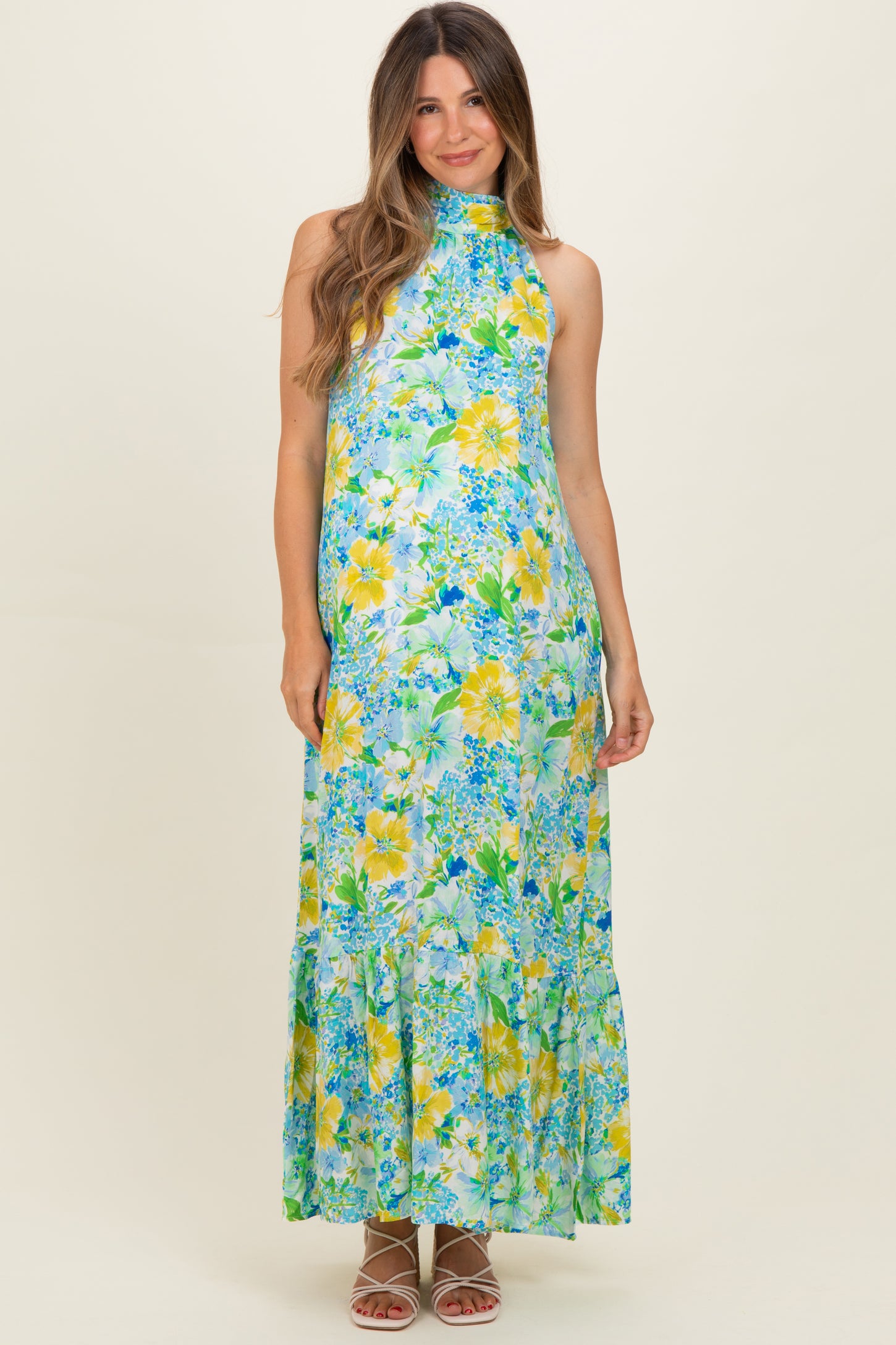 woman wearing a floral halter neck maxi maternity dress in shades of blue and yellow