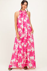 woman wearing a long flowy maxi dress with a pink floral print and a halter neck design
