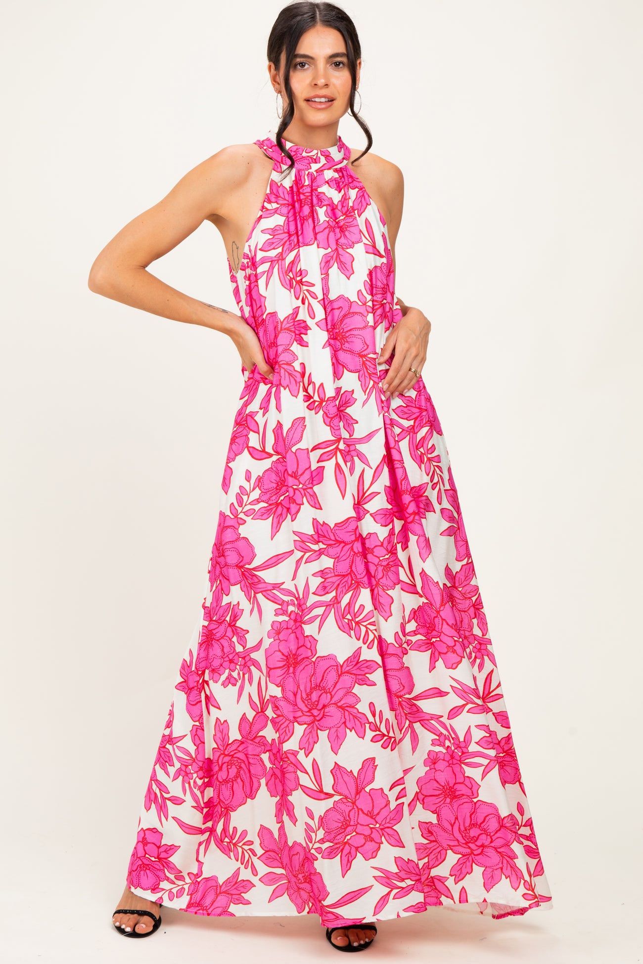 woman wearing a halter neck pink floral maxi dress with a flowy silhouette