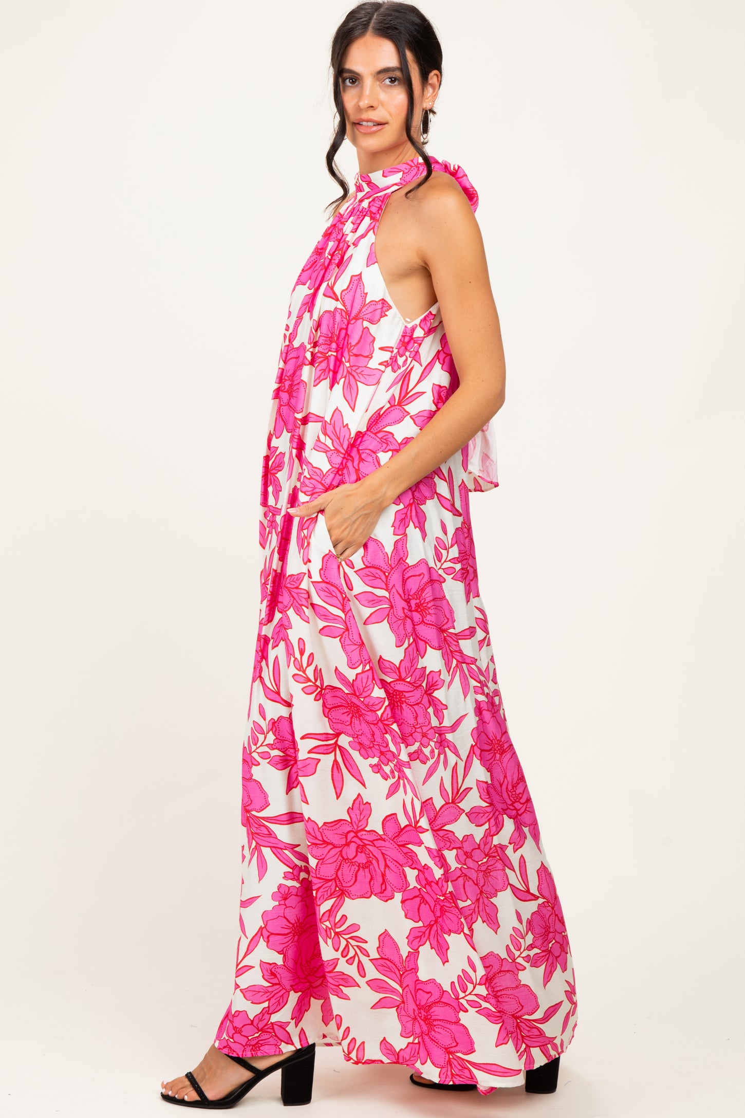 woman wearing a pink floral maxi dress with a halter neckline and side pockets