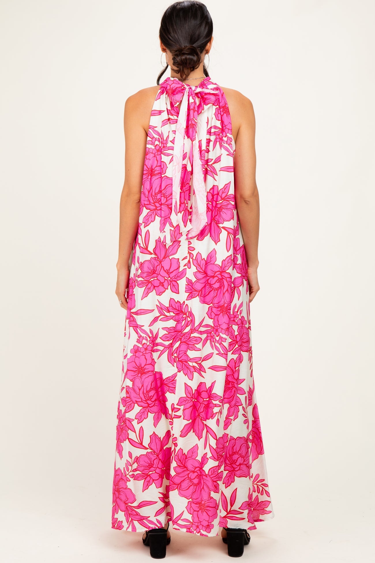 woman wearing a floral pink maxi dress with a halter neck and open back