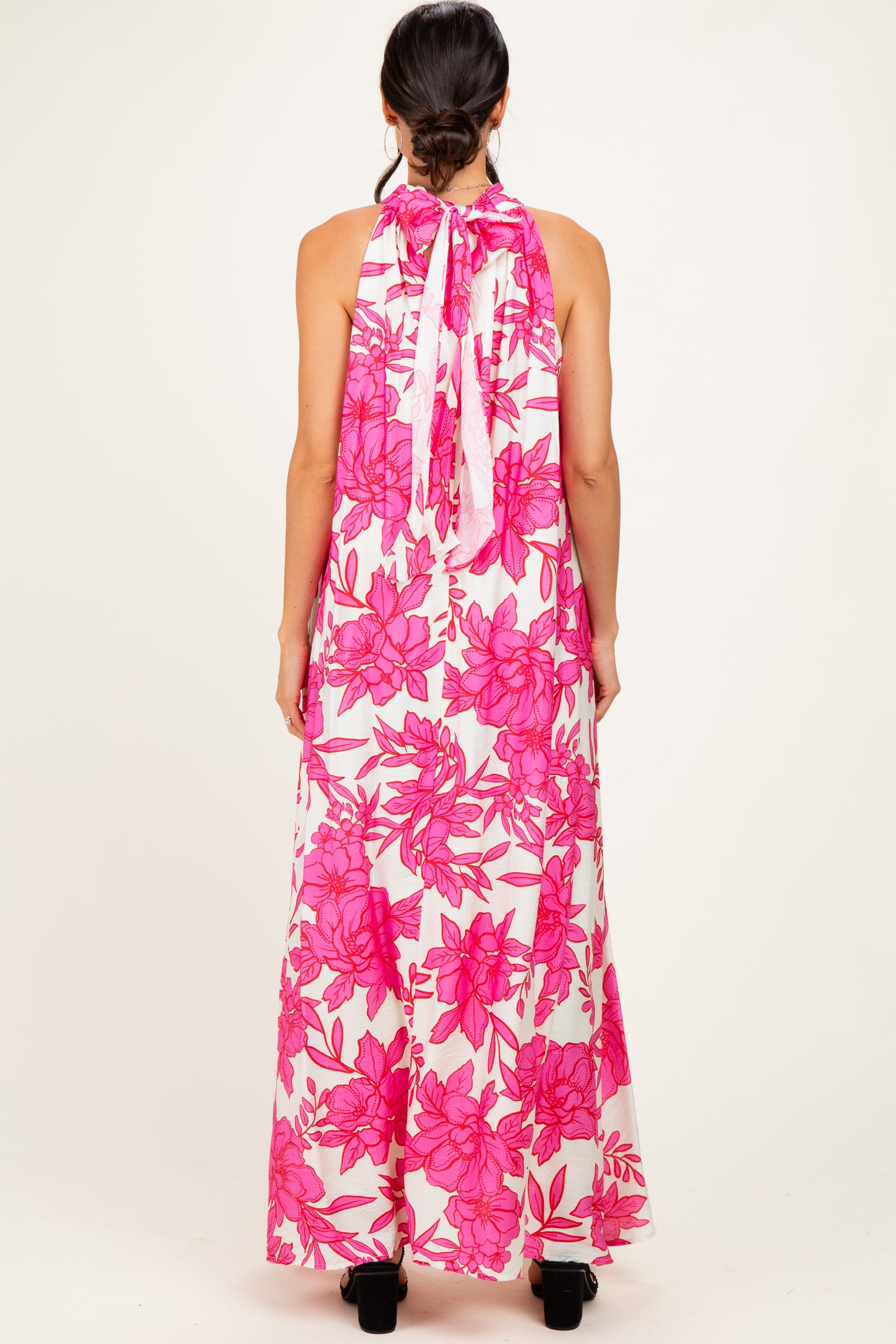 woman wearing a floral pink maxi dress with a halter neck and open back