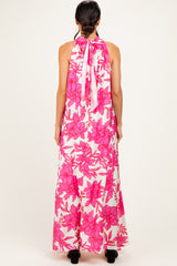 woman wearing a floral pink maxi dress with a halter neck and open back