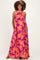 woman wearing a flowy purple maternity dress with bright orange floral pattern and halter neckline, smiling and posing