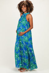 woman wearing a blue floral maternity maxi dress and cradling her baby bump