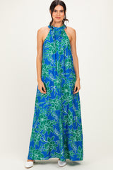 woman wearing a blue floral halter neck maxi dress with green floral patterns