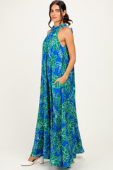 woman wearing a blue floral halter neck maxi dress with pockets and loose fit