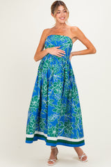 woman wearing a strapless blue floral maternity maxi dress and cradling her baby bump
