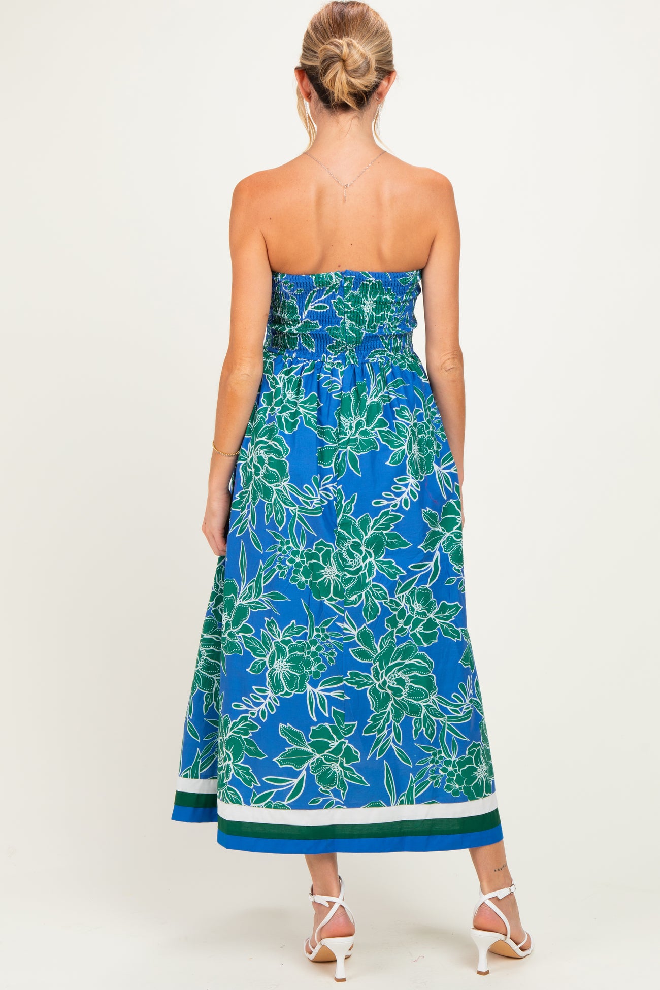 woman wearing a blue floral strapless maternity maxi dress with smocking and a flowy hemline