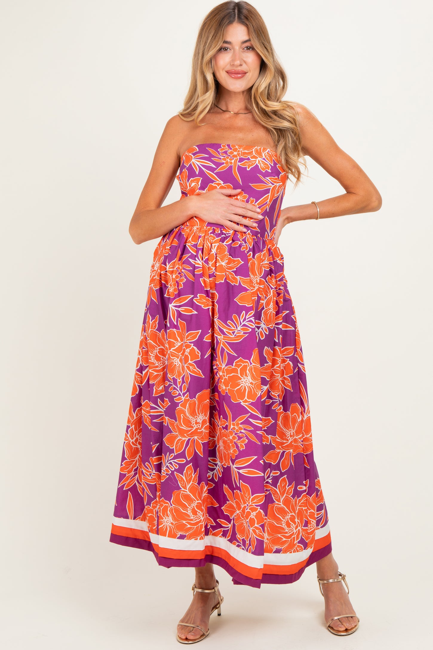 woman wearing a purple floral strapless maternity dress with a baby bump visible