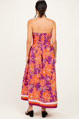woman wearing a purple floral strapless maxi dress with orange flowers and a smocked bodice, view from the back
