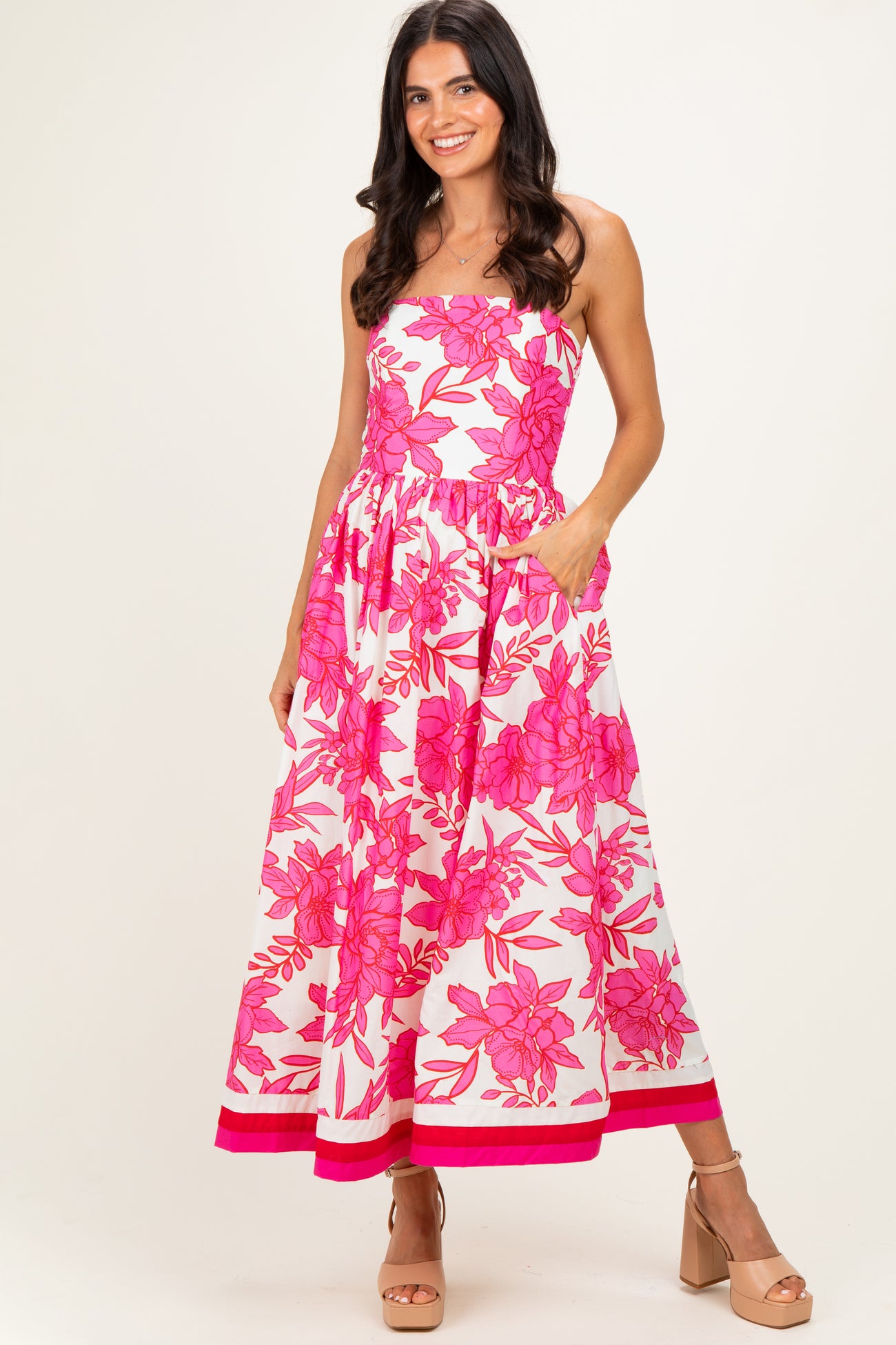 woman wearing a strapless pink floral maxi dress with an elastic waist and side pockets