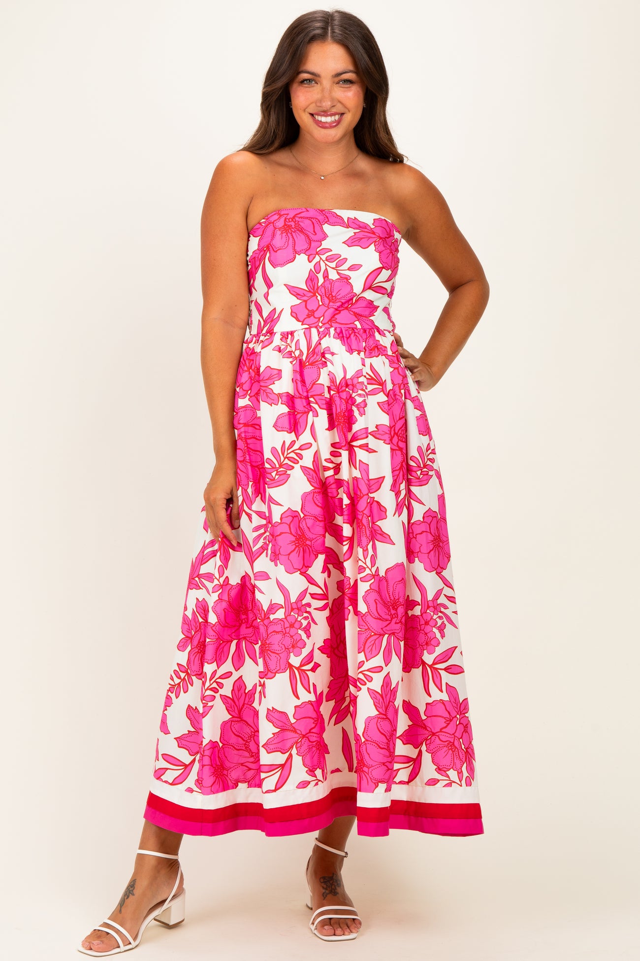 woman wearing a strapless pink floral maternity dress with a flowy skirt and a tiered hem