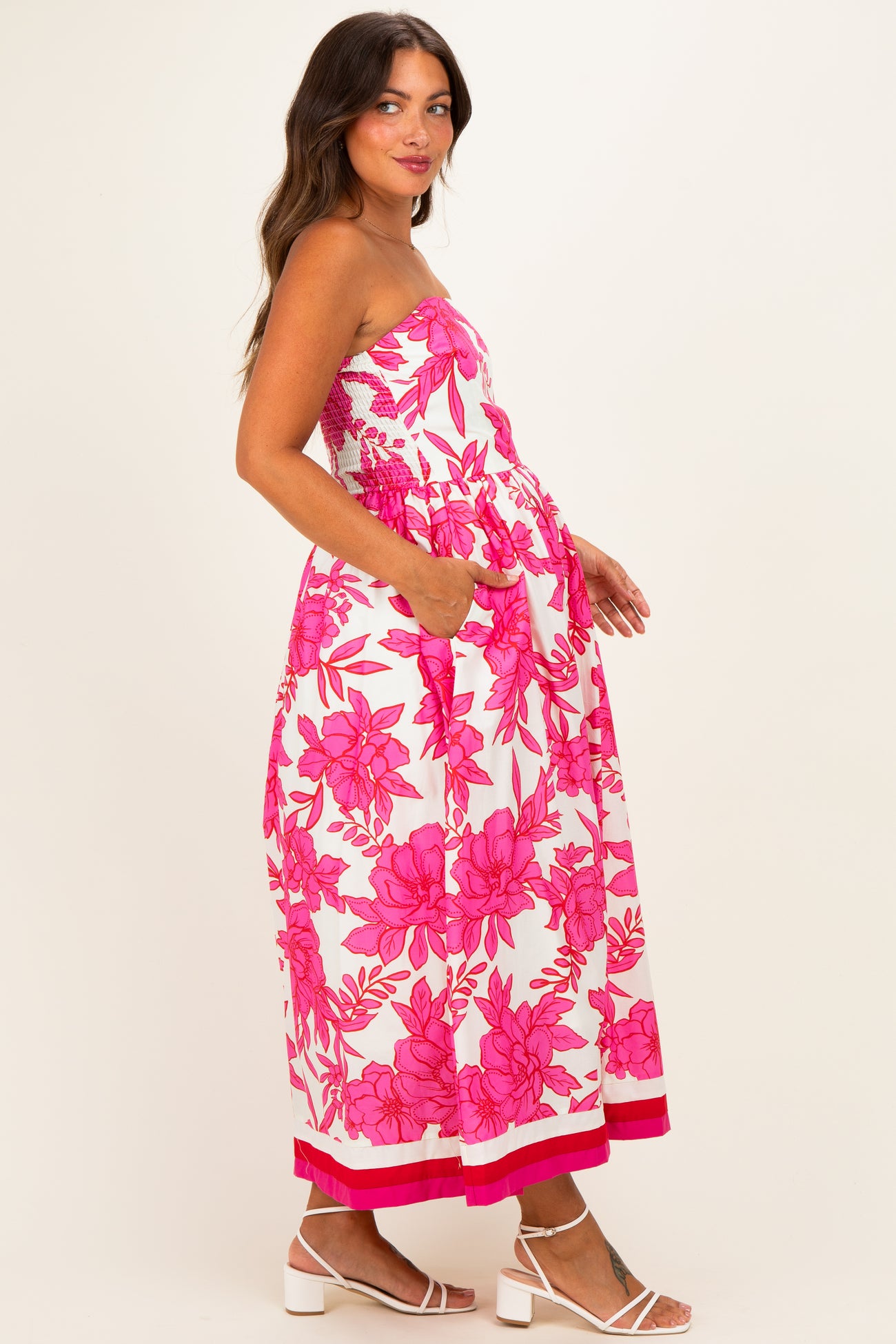 woman wearing a strapless pink floral maternity dress with pockets and a flowy silhouette