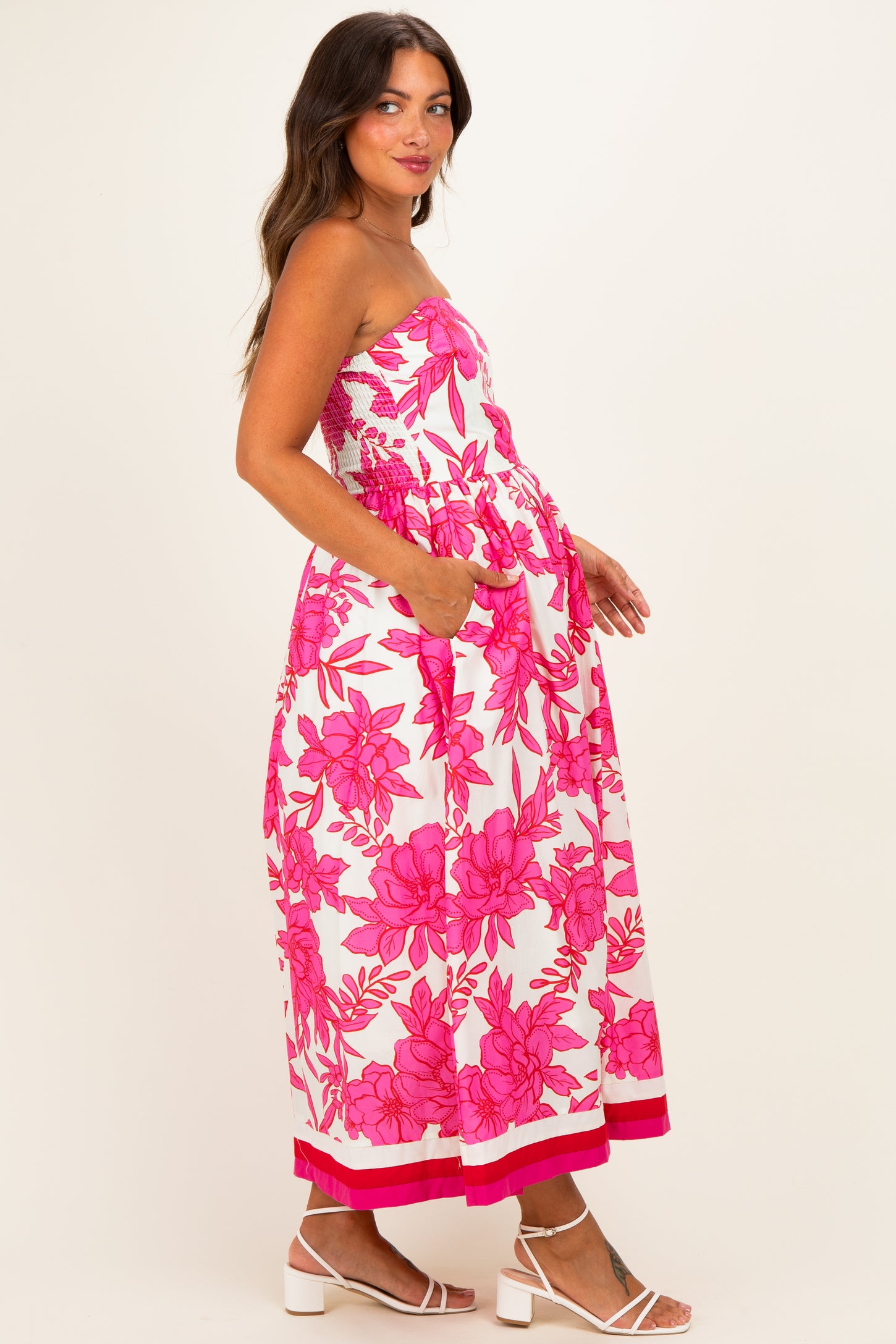 woman wearing a strapless pink floral maternity dress with pockets and a flowy silhouette