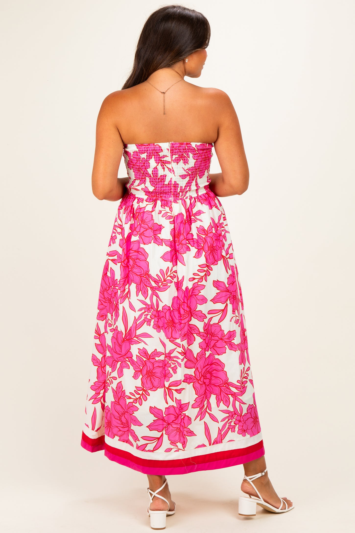 woman wearing a pink floral strapless maternity maxi dress with a smocked bodice and ankle-length hem