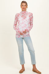 woman wearing a sheer floral maternity top in pink and white with a baby bump, paired with light blue jeans