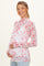 woman wearing a floral sheer maternity top with a high neckline and long sleeves, highlighting her baby bump