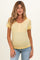 woman wearing a light yellow maternity top with short ruffled sleeves and button detail, showing a baby bump