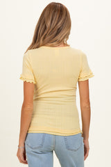 woman wearing a light yellow short sleeve maternity top with ruffle details and a snug fit, viewed from the back