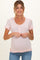 woman wearing a light pink maternity top with short sleeves and scalloped edges, showcasing a visible baby bump