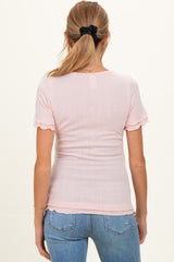 woman wearing a light pink short sleeve maternity top with scalloped edges and a fitted style, showing her back