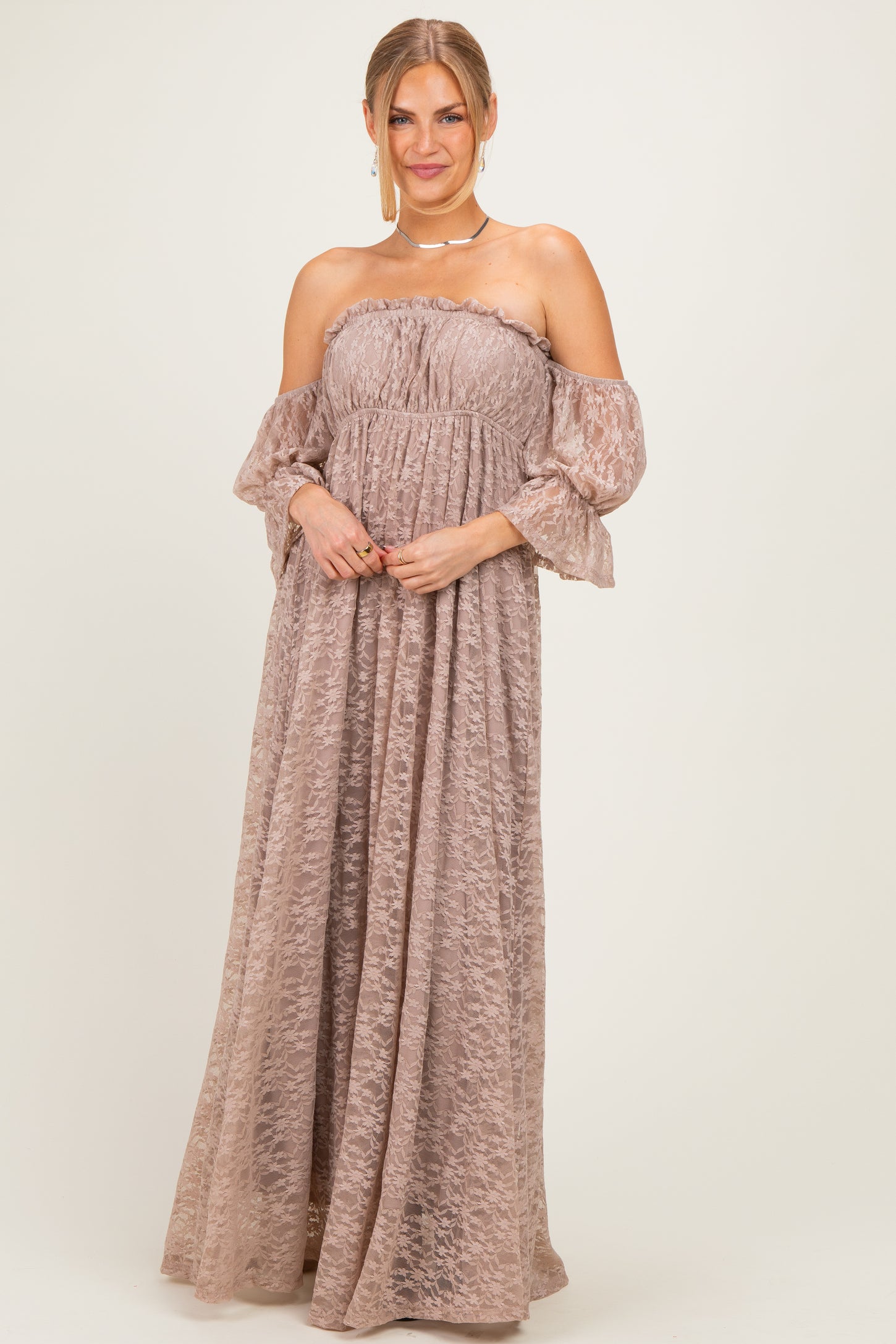 woman wearing a strapless blush maxi dress with ruffled off-the-shoulder sleeves and textured fabric.