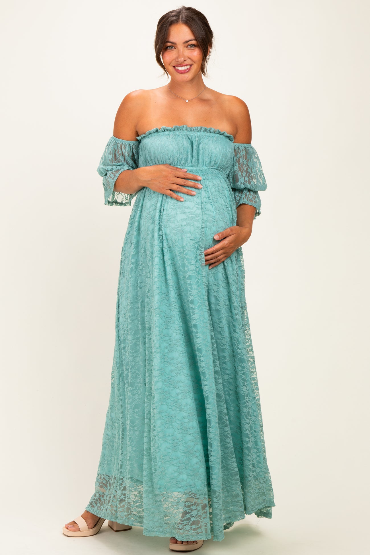 woman wearing a light blue off-the-shoulder maternity maxi dress and holding her baby bump