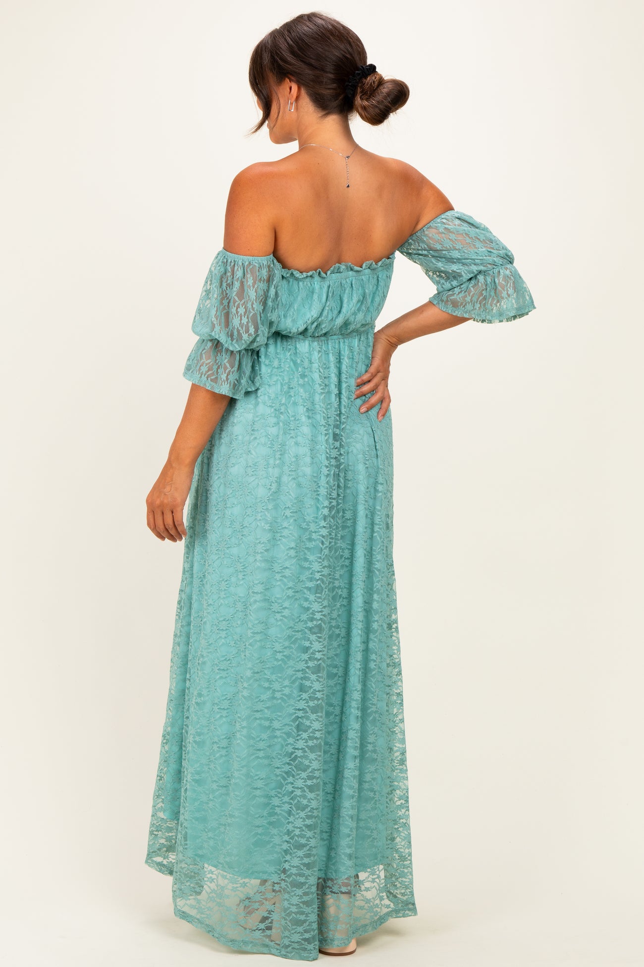 woman wearing a teal off-shoulder lace maternity maxi dress with flutter sleeves and a cinched waist