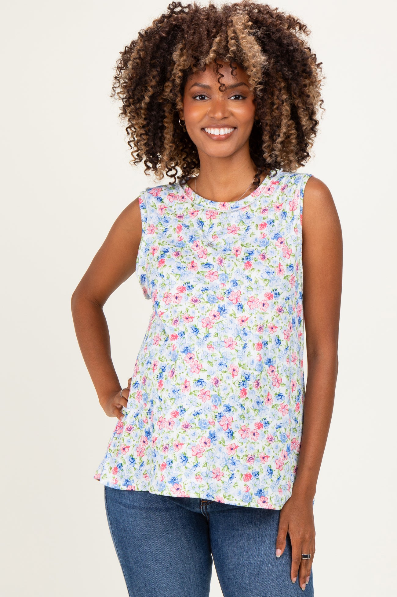 woman wearing a floral sleeveless maternity top with a relaxed fit and baby bump visible, paired with blue jeans